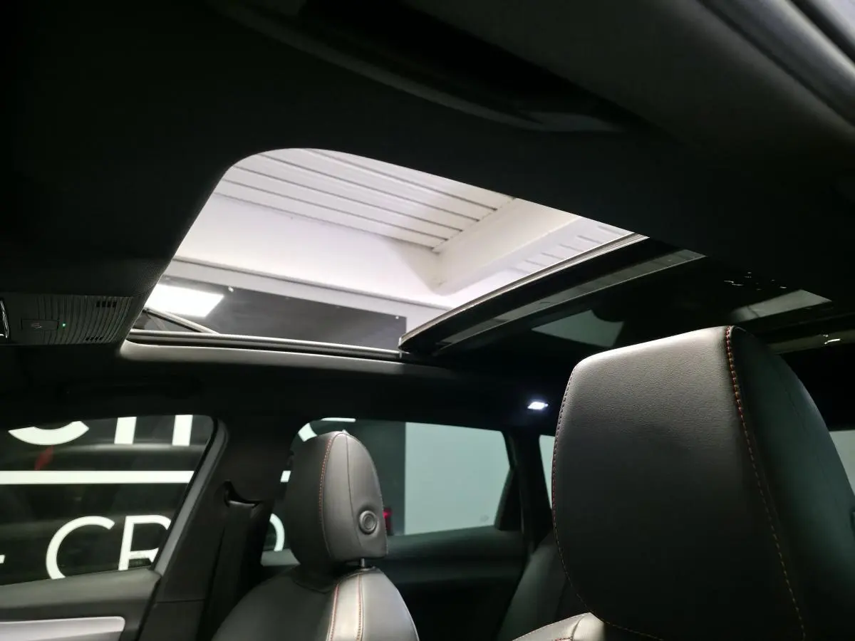 Vue intérieure montrant le toit ouvrant panoramique et les sièges sport en suédine noire avec surpiqûres rouges du SEAT Leon Sportstourer.