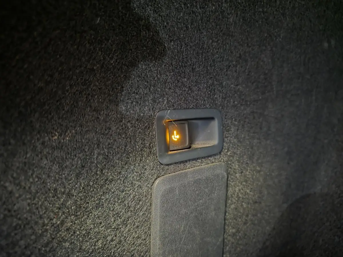 Gros plan sur le bouton d’abattement électrique de la banquette arrière dans le coffre d’un SEAT Leon Sportstourer gris.