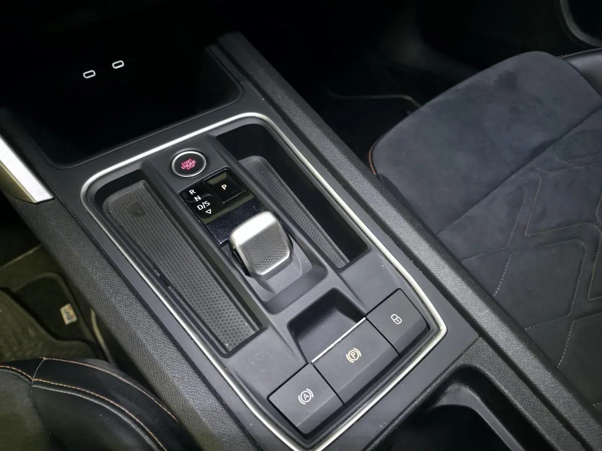 Gros plan sur la console centrale avec levier de boîte automatique et sièges sport en suédine noire du SEAT Leon Sportstourer.