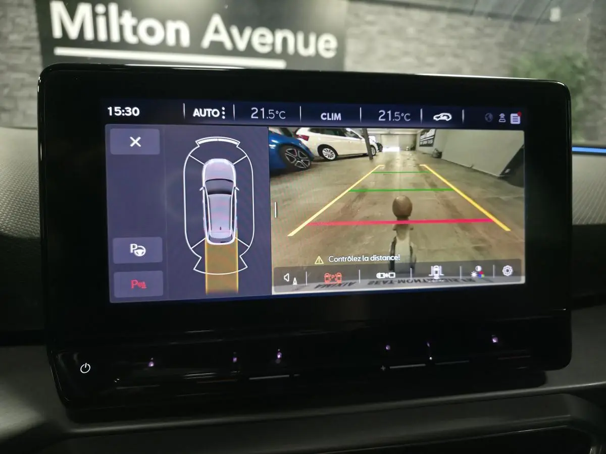 Écran tactile intérieur montrant la caméra de recul et l'aide au stationnement du SEAT Leon Sportstourer gris.