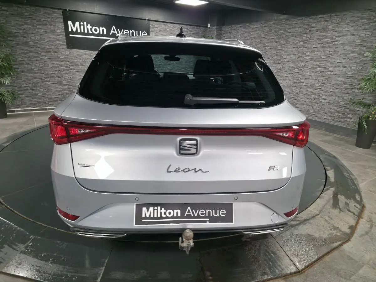 Vue arrière d'un SEAT Leon Sportstourer gris avec hayon électrique et crochet d'attelage escamotable visible.