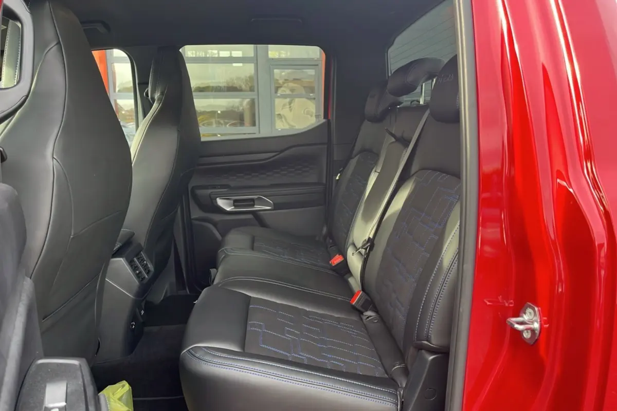 Vue latérale intérieure sur les sièges arrière en cuir noir avec surpiqûres bleues du Ford Ranger 3.0 V6 Lucid Red 2025.