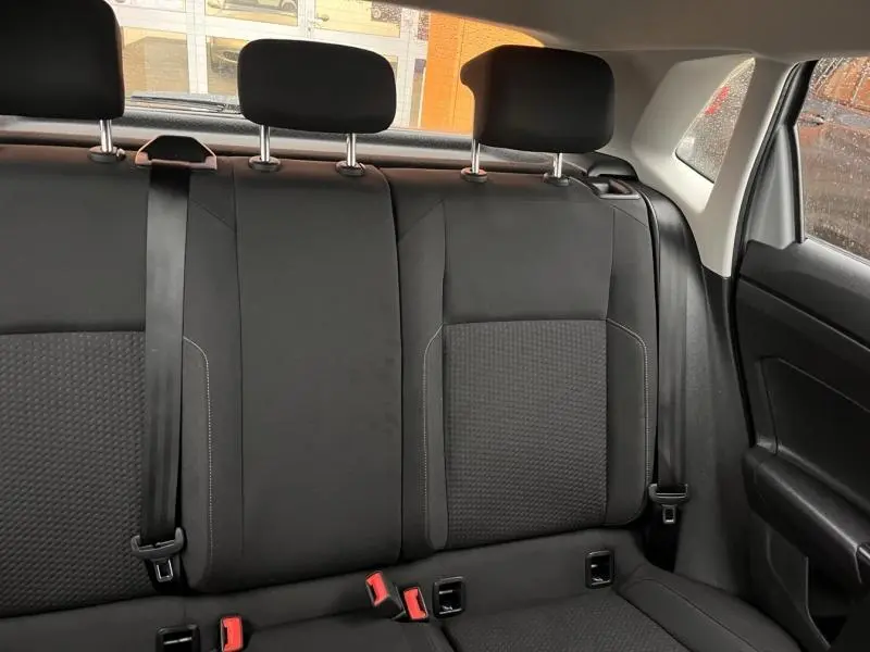 Vue intérieure arrière montrant la banquette tissu noir avec appuie-têtes et ceintures de sécurité de la Volkswagen Polo gris Urano.