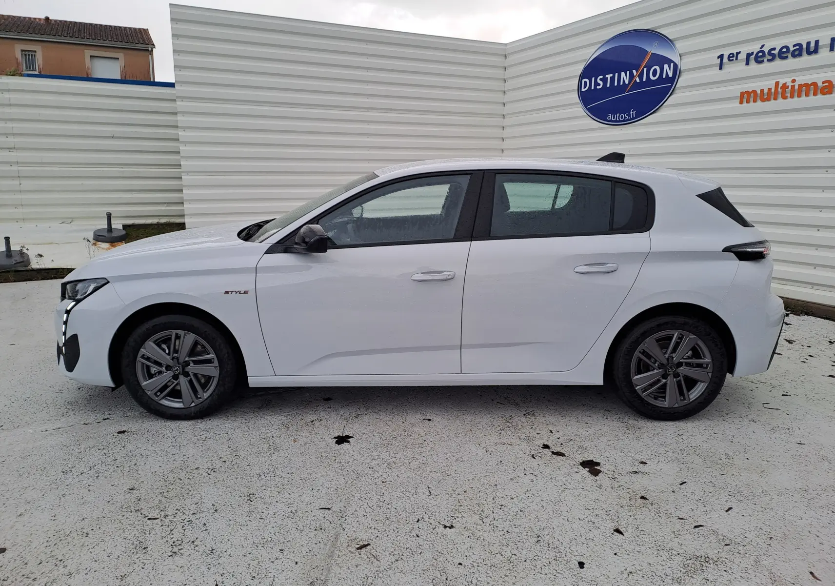 Profil latéral droit d'une Peugeot 308 blanche Okenite, version BlueHDi 130ch Style avec jantes alliage et feux arrière noirs.