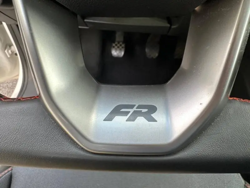 Gros plan sur le volant avec logo FR de la SEAT Ibiza 1.0 TSI 115cv FR, intérieur noir et pédales en métal visibles.