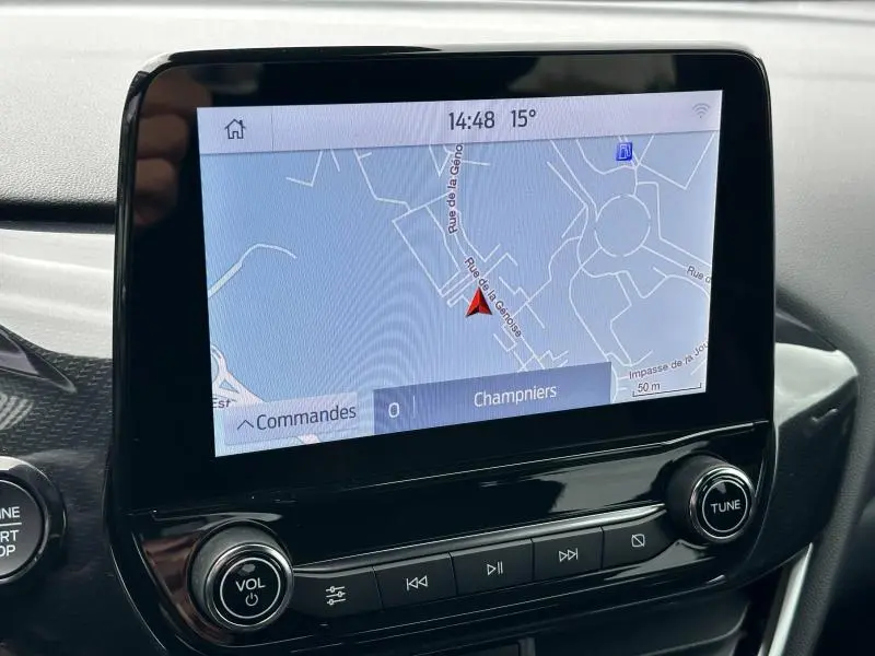 Écran tactile central du Ford Puma 2024 affichant la navigation, entouré de commandes audio noires brillantes.