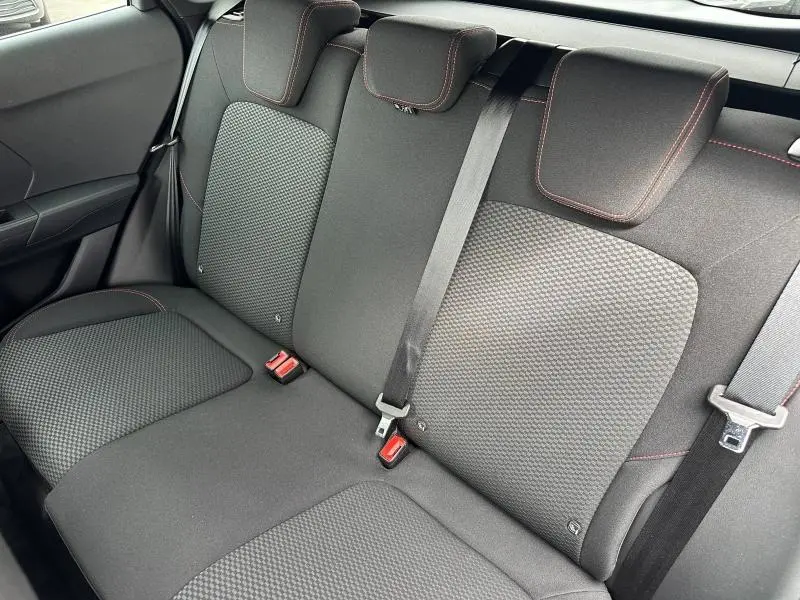 Vue intérieure de la banquette arrière du Ford Puma 2024, tissu noir avec surpiqûres rouges et ceintures de sécurité visibles.
