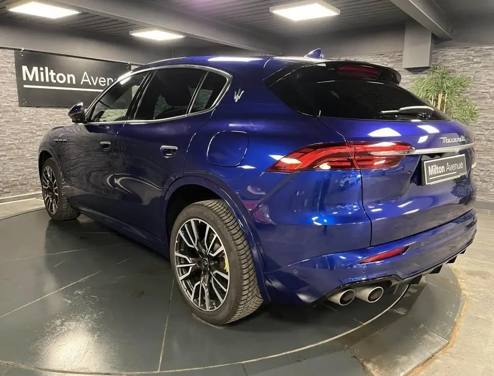 Vue 3/4 arrière droite d'une Maserati Grecale bleu avec étriers de freins jaunes et jantes noires brillantes.
