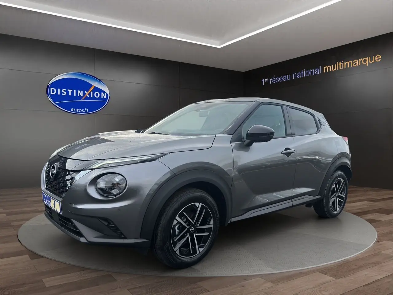 Nissan Juke Full Hybrid gris squale en 3/4 avant droit, avec jantes alliage noires et calandre distinctive.