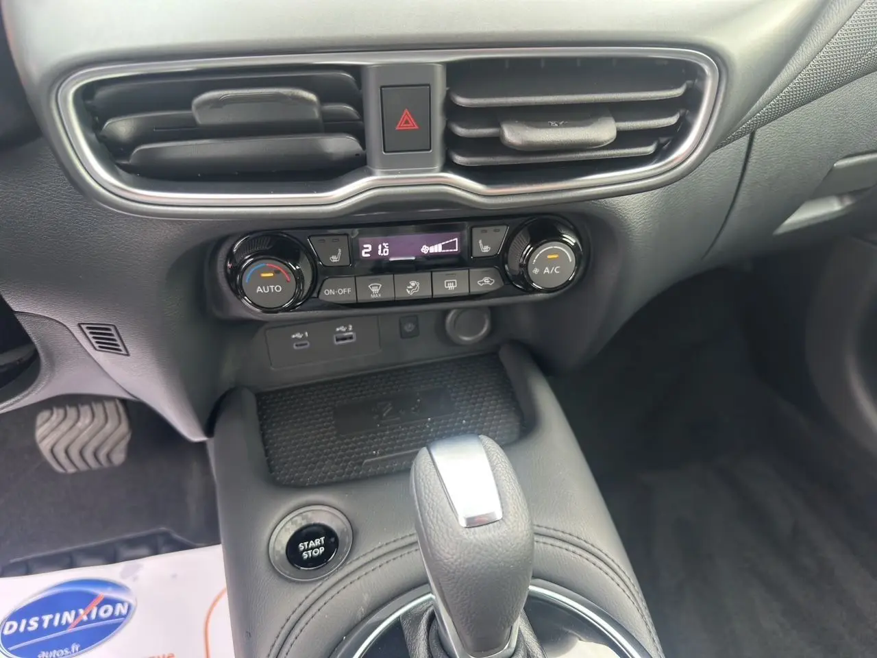 Gros plan sur la console centrale du Nissan Juke gris, montrant la commande de climatisation et le levier de vitesse automatique.