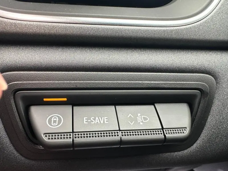 Gros plan sur les boutons de commande E-SAVE et réglage des phares dans l'habitacle du Renault Captur rouge 2025.