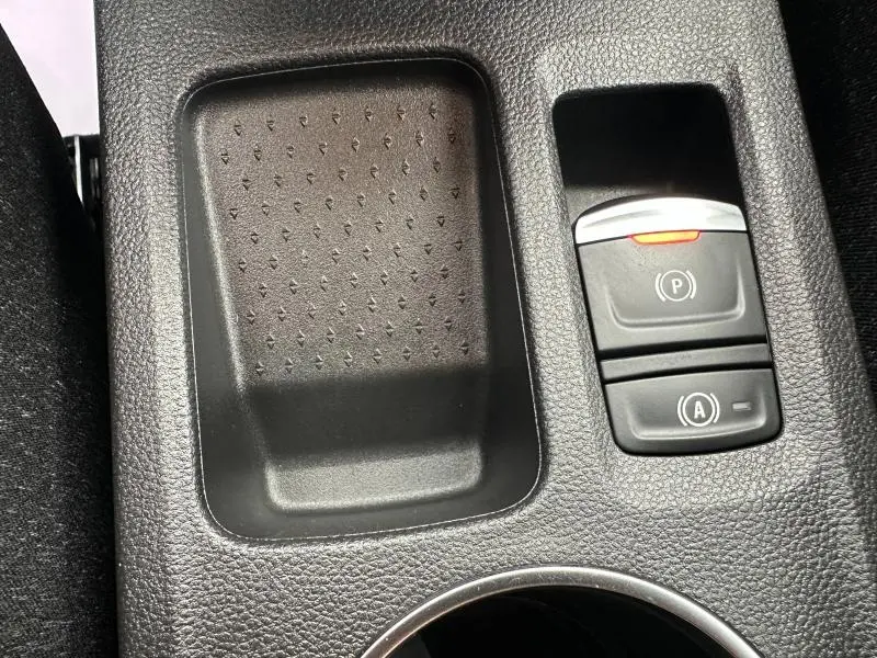 Gros plan sur la console centrale du Renault Captur 2025, montrant les boutons de frein à main électronique et auto hold.