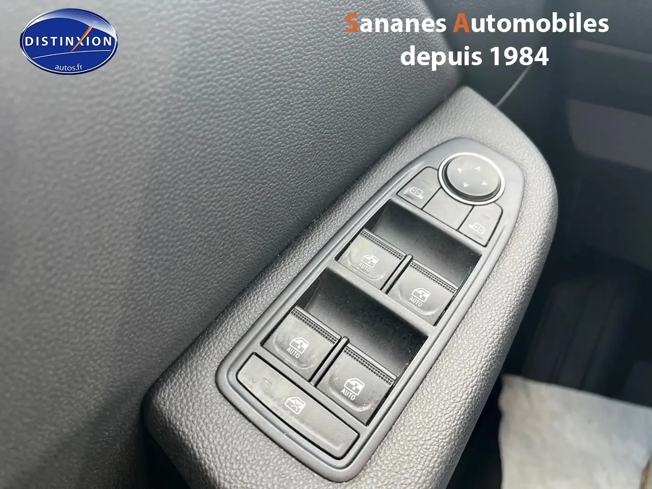 Gros plan sur les commandes des vitres électriques côté conducteur d'une Renault Clio Bleu Iron, finition Intens 2021.