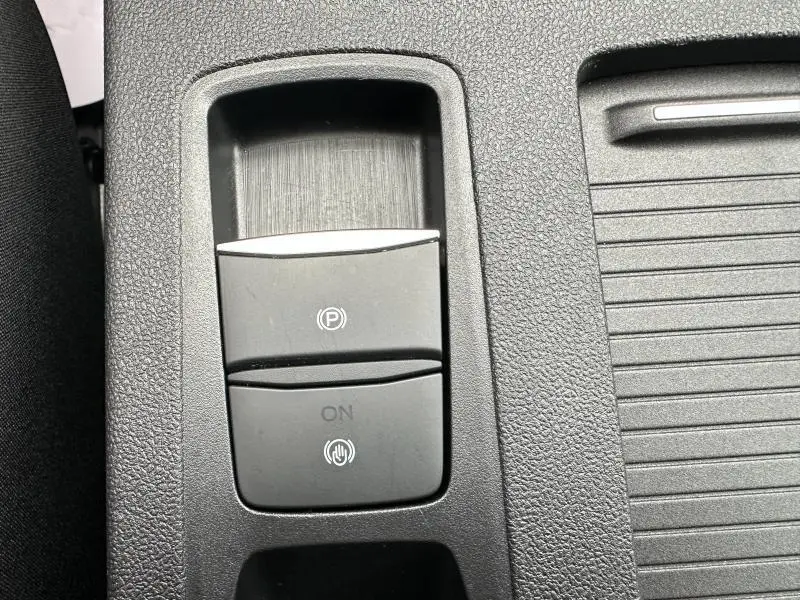 Gros plan sur le bouton de frein à main électronique noir dans la console centrale du Ford Kuga gris Solar Métallisée 2024.