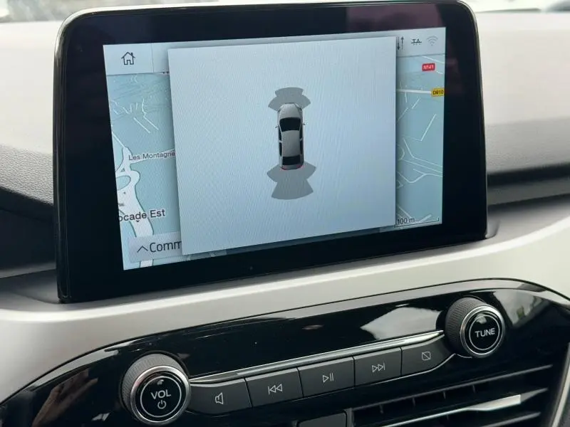 Écran tactile central du Ford Kuga 2024 affichant la caméra de recul et la carte GPS en arrière-plan.