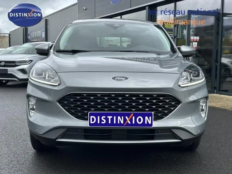 Vue frontale d'un Ford Kuga 1.5 EcoBoost gris Solar métallisé avec calandre noire et phares LED allumés.