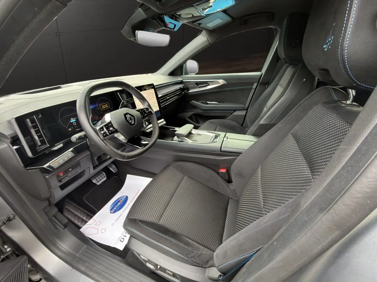 Intérieur avant droit du Renault Austral Iconic Esprit Alpine 2023, sièges noirs avec surpiqûres bleues et volant multifonctions.