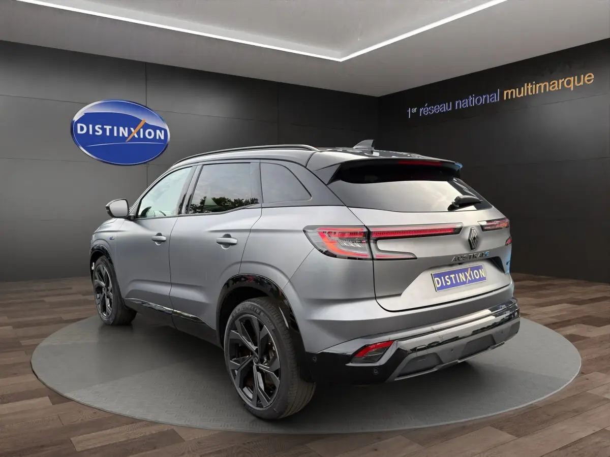 Vue 3/4 arrière droite d'un Renault Austral gris foncé avec feux arrière LED et jantes noires en showroom.