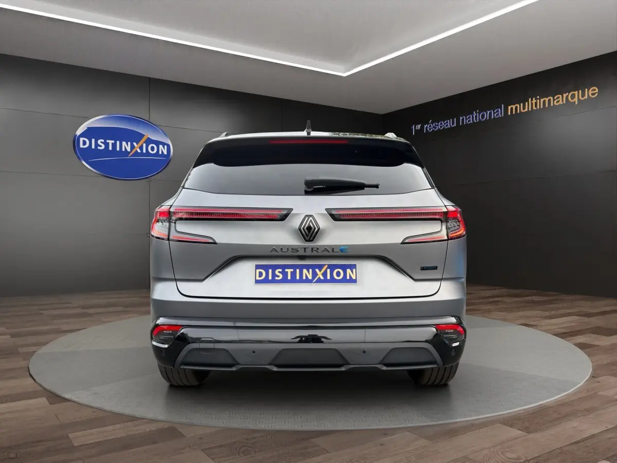 Vue arrière d'une Renault Austral gris foncé avec feux LED étirés et logo Distinxion en arrière-plan.