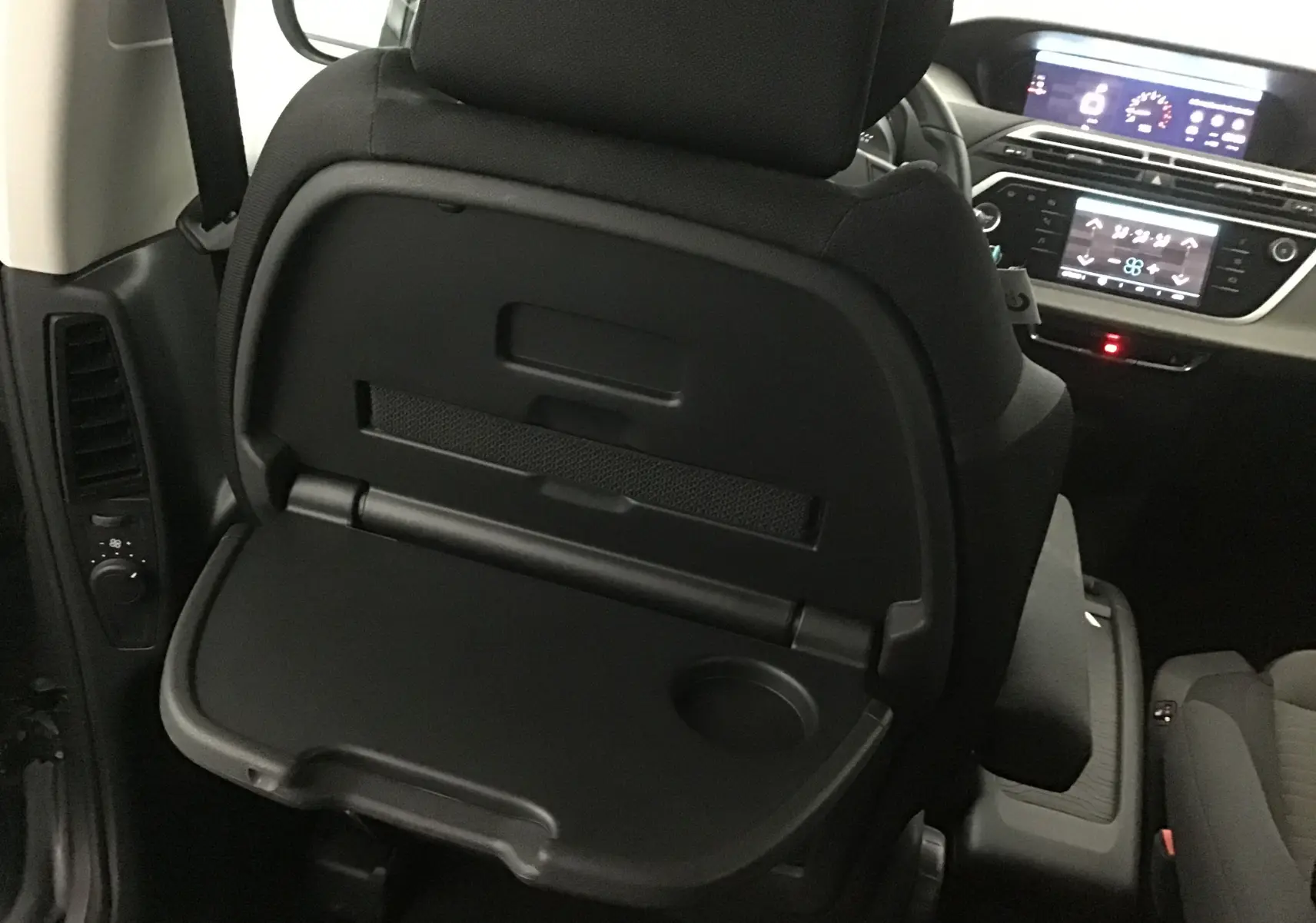 Vue intérieure du Citroën Grand C4 Spacetourer 2021 montrant le plateau rabattable noir fixé au dossier du siège avant côté passager.