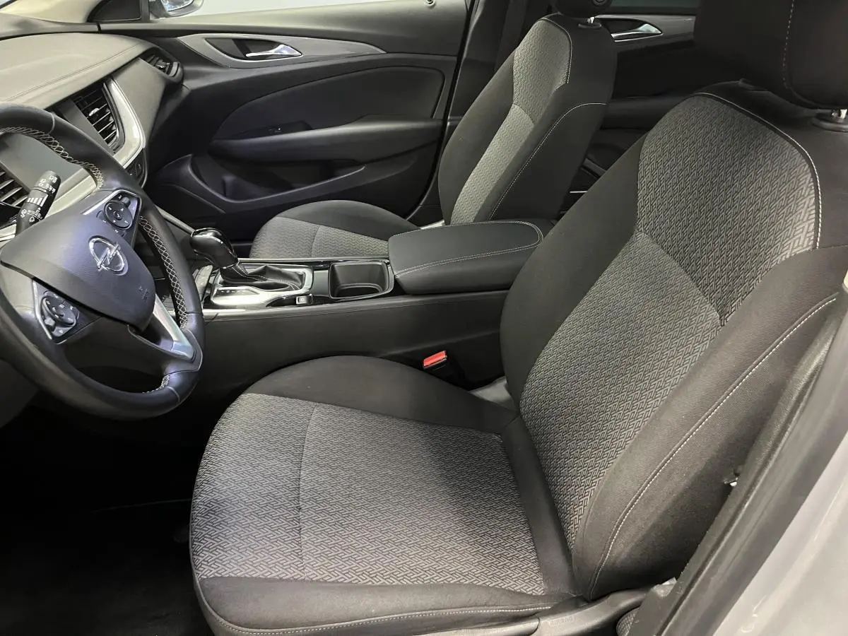 Intérieur avant droit de l’Opel Insignia gris, sièges tissu anthracite et volant cuir multifonctions visible.