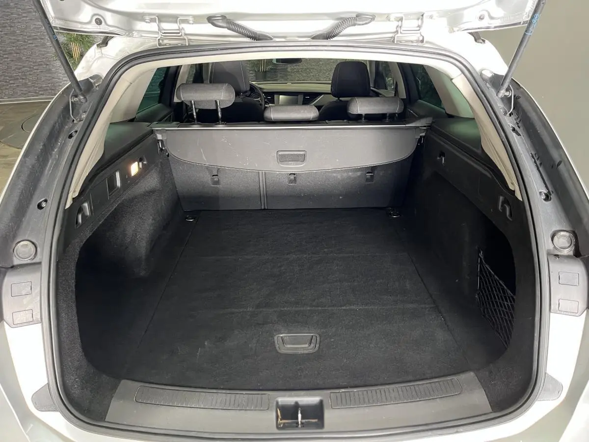 Coffre ouvert vu de l'arrière d'une Opel Insignia Sports Tourer gris, montrant un espace de chargement propre et spacieux.
