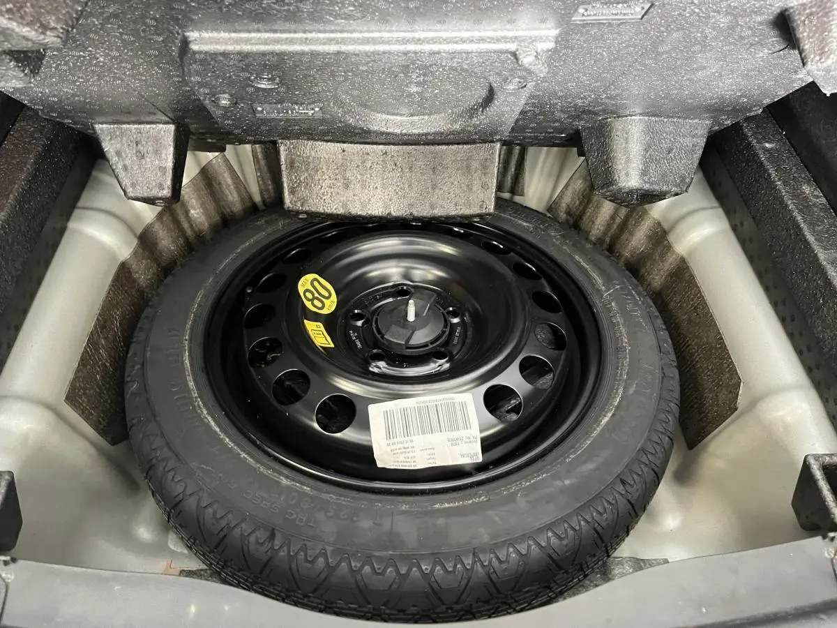 Roue de secours noire dans le coffre de l'Opel Insignia Sports Tourer gris, vue en plongée.