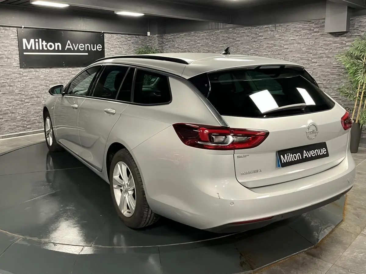 Vue 3/4 arrière droite d'une Opel Insignia Sports Tourer gris métallisé avec vitres surteintées en showroom.