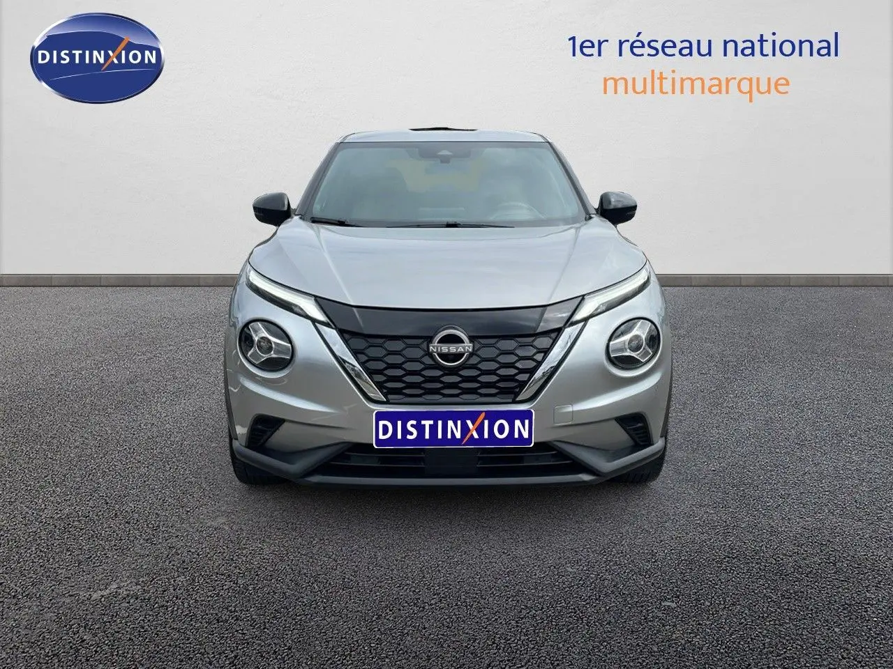 Vue frontale d'un Nissan Juke Hybrid 143ch Business gris perle métal avec calandre noire et phares ronds distinctifs.