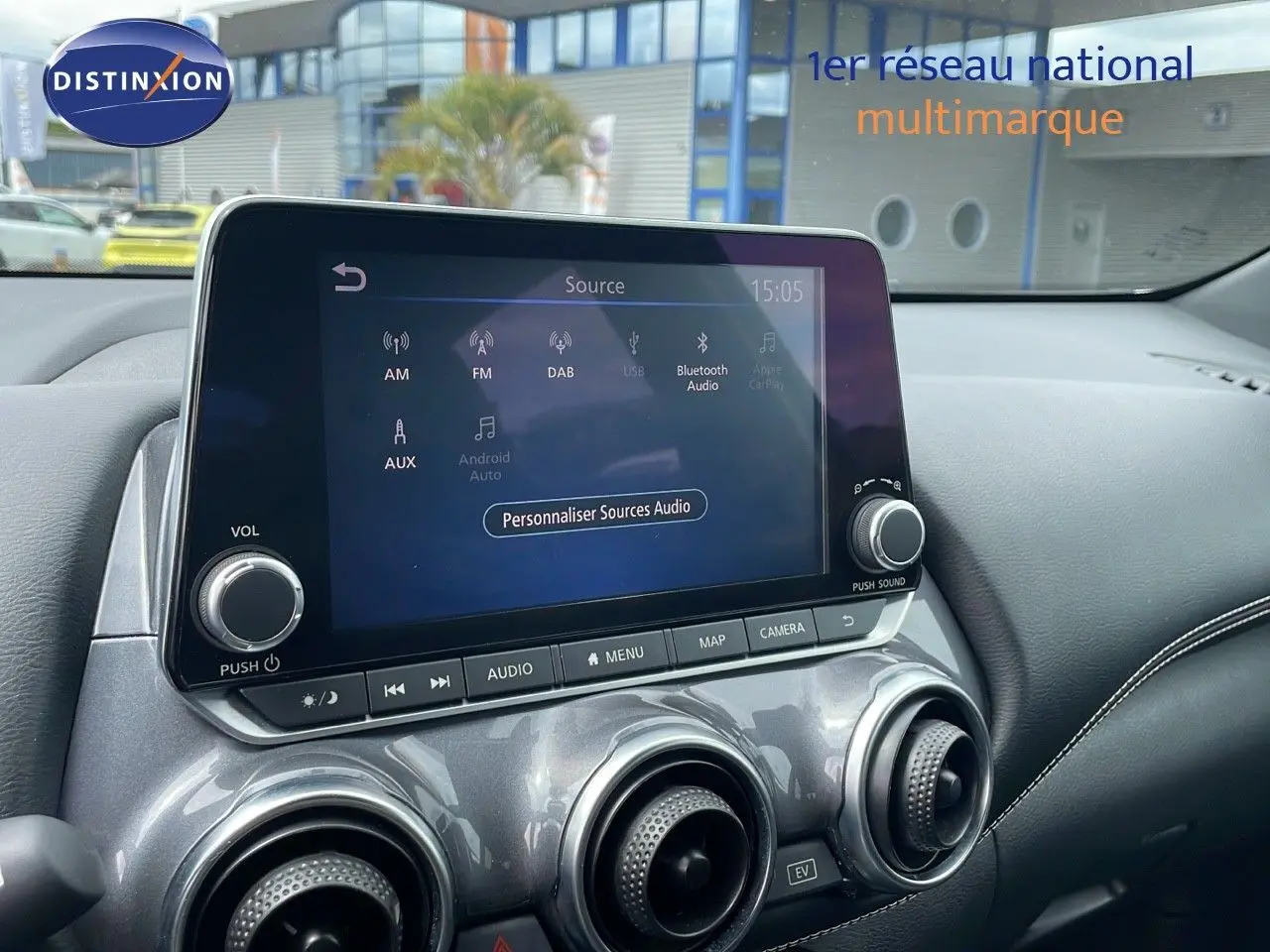 Écran tactile central et commandes de climatisation du Nissan Juke Hybrid 143ch Business 2023 en gris perle métal.