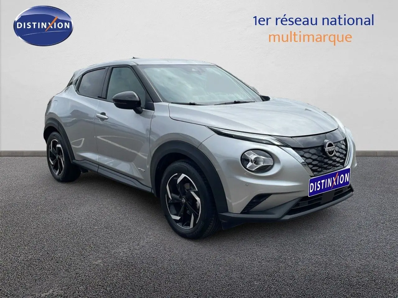 Nissan Juke Hybrid gris perle métal vu en 3/4 avant droit avec calandre noire et jantes bi-ton.