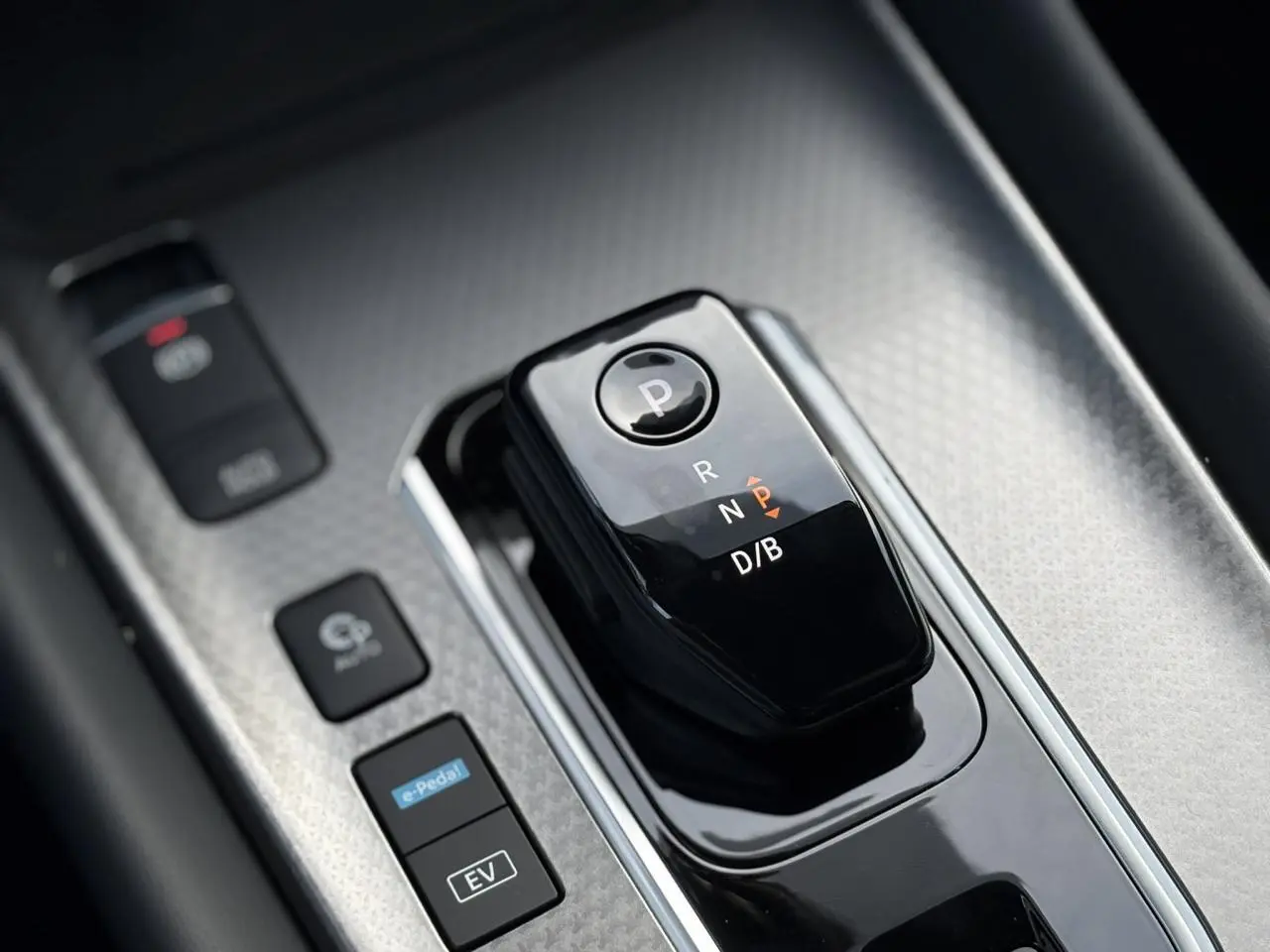 Gros plan sur la commande de boîte automatique noire du Nissan Qashqai blanc nacré, avec boutons e-Pedal et mode EV visibles.