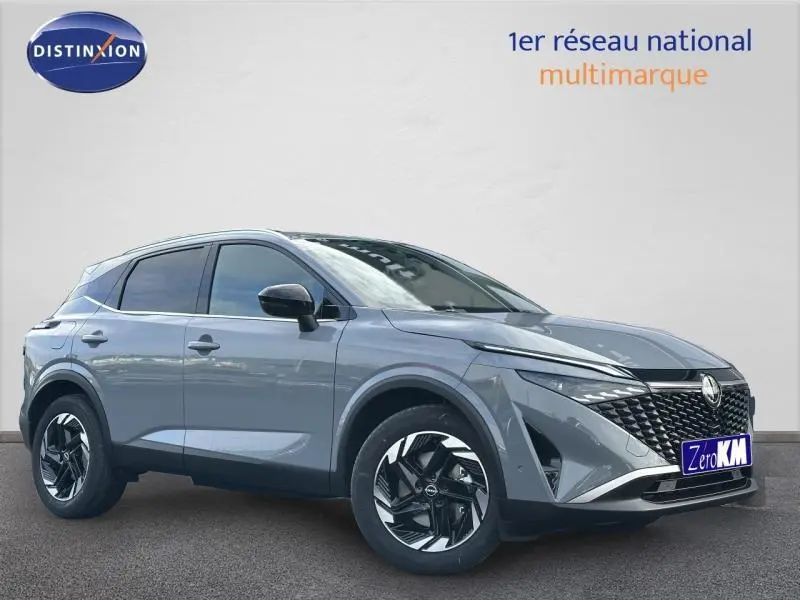 Nissan Qashqai Hybrid e-POWER 2025 en gris Argile, vue 3/4 avant mettant en valeur sa calandre et ses jantes noires.