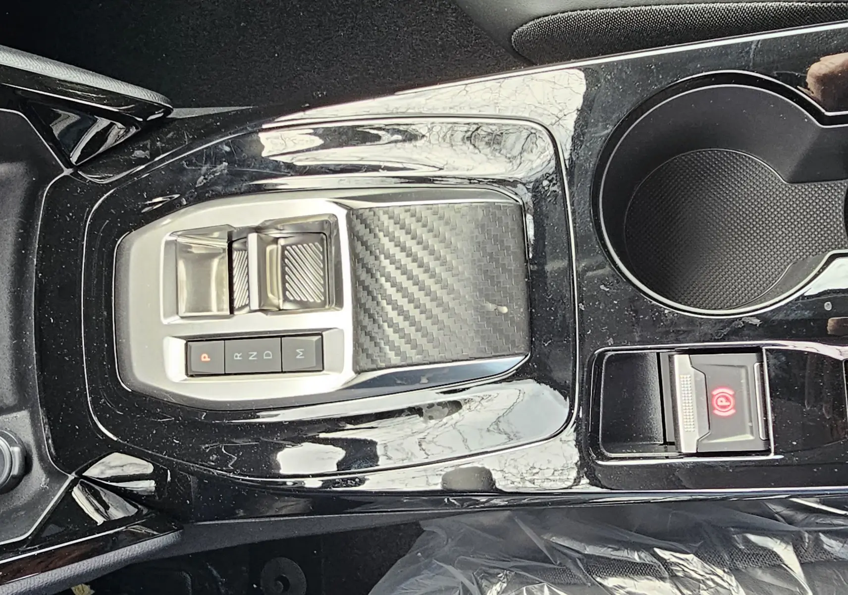 Vue rapprochée de la console centrale noire brillante de la Peugeot 208 110 hybrid Allure avec sélecteur de boîte auto et commandes Drive Mode.