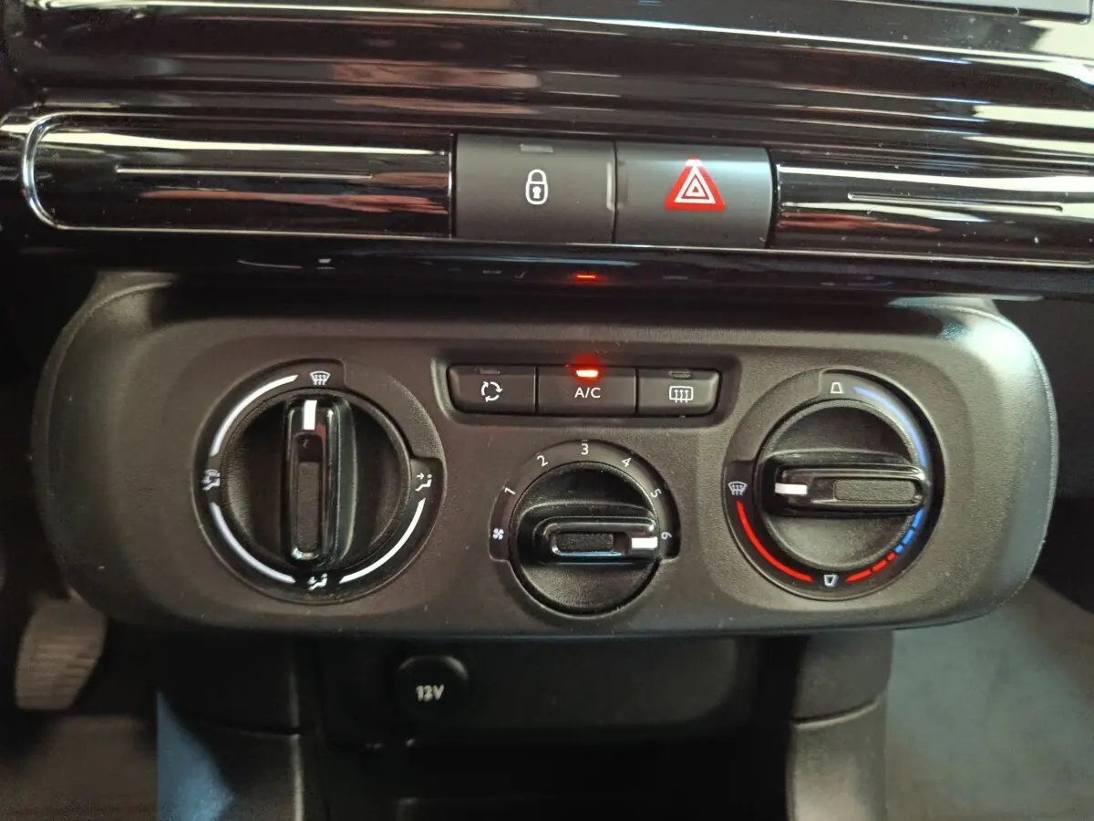 Vue rapprochée du tableau de bord central de la Citroën C3 blanche, montrant les commandes de climatisation et les boutons de sécurité.