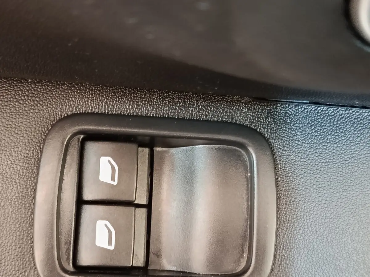 Gros plan sur les commandes des vitres électriques côté conducteur d'une Citroën C3 blanche, intérieur noir.
