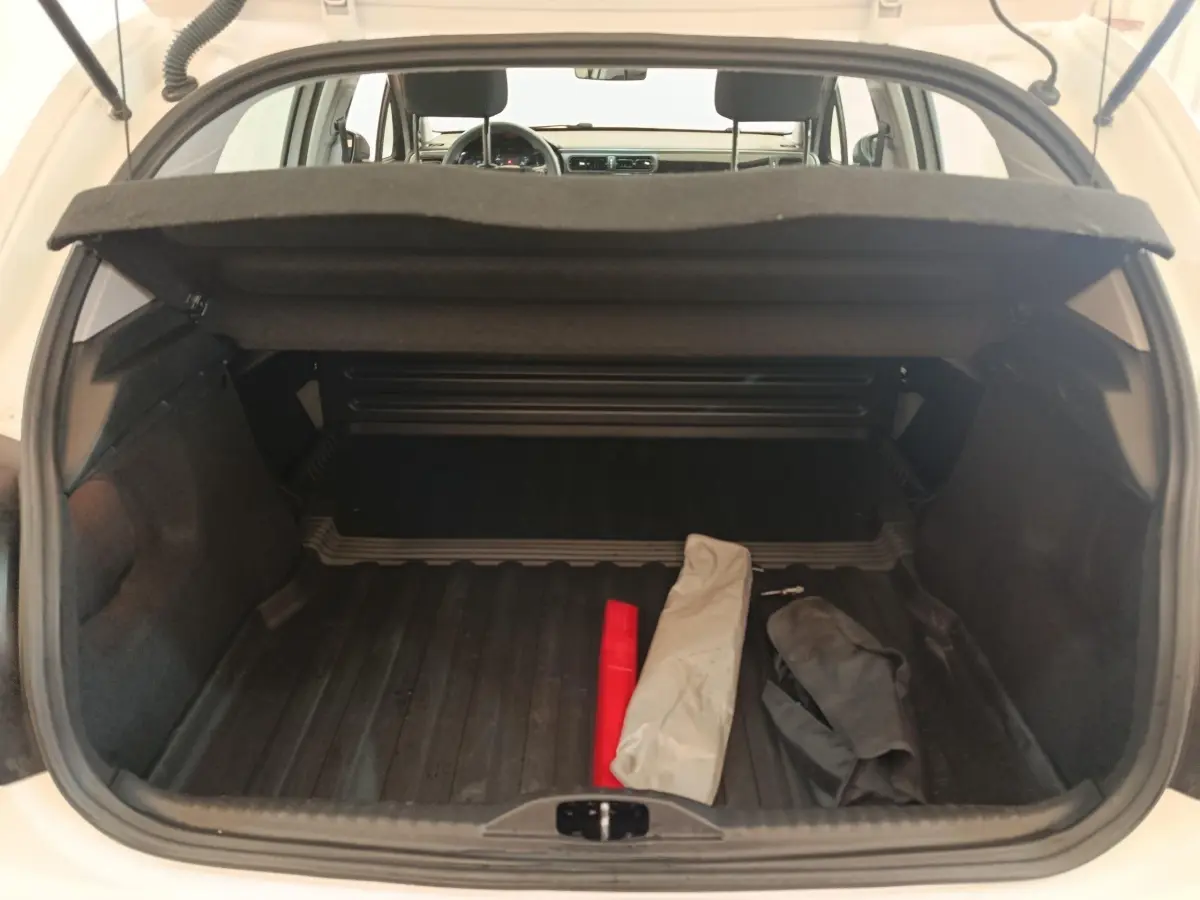 Vue arrière du coffre ouvert d'une Citroën C3 blanche 2021, montrant un espace de rangement avec objets posés.