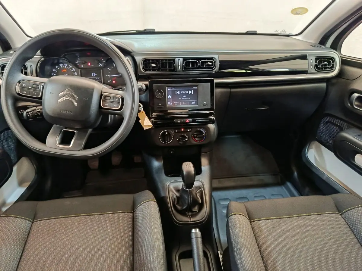 Vue intérieure avant de la Citroën C3 blanche 2021, volant multifonctions, tableau de bord noir avec écran tactile central.