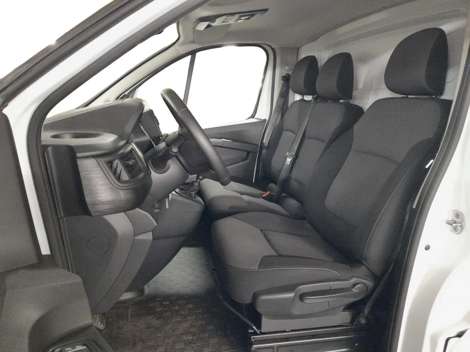 Vue intérieure côté gauche du Renault Trafic Fourgon blanc minéral 2024, montrant les sièges tissu noirs et le tableau de bord.