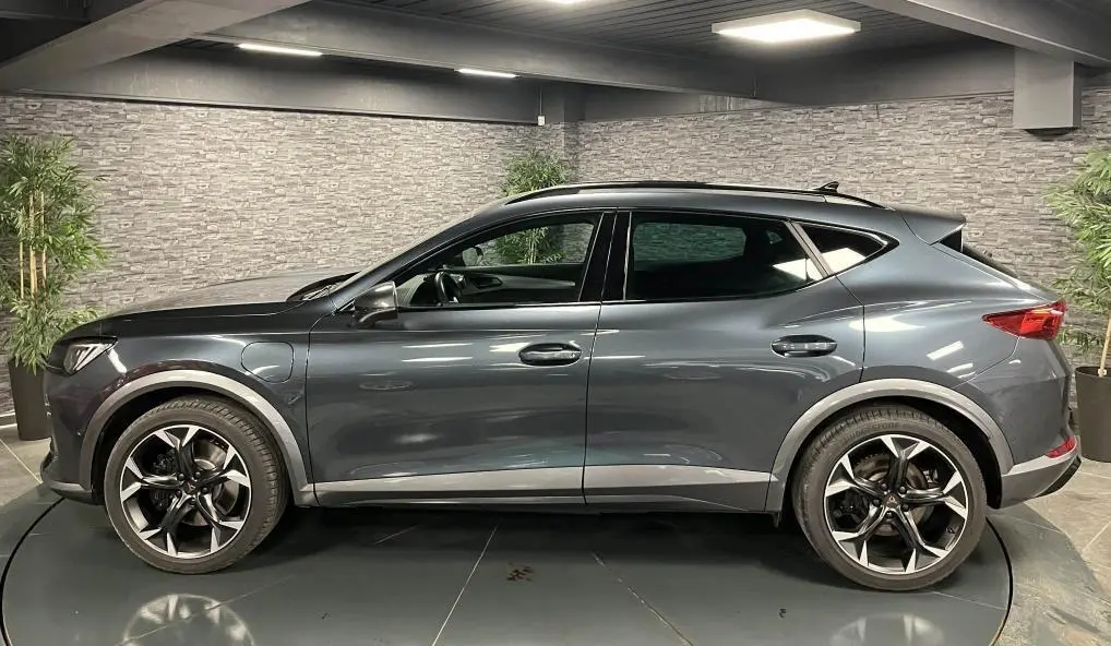 Profil côté gauche d'un CUPRA Formentor gris magnétique 2023 avec jantes alliage 19 pouces et prises de recharge visibles.