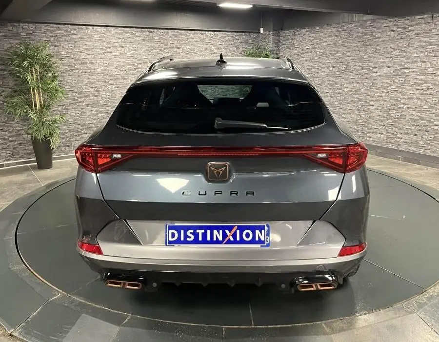 Vue arrière d'un CUPRA Formentor gris magnétique avec bandeau LED arrière Infinite Light et double sortie d'échappement copper.