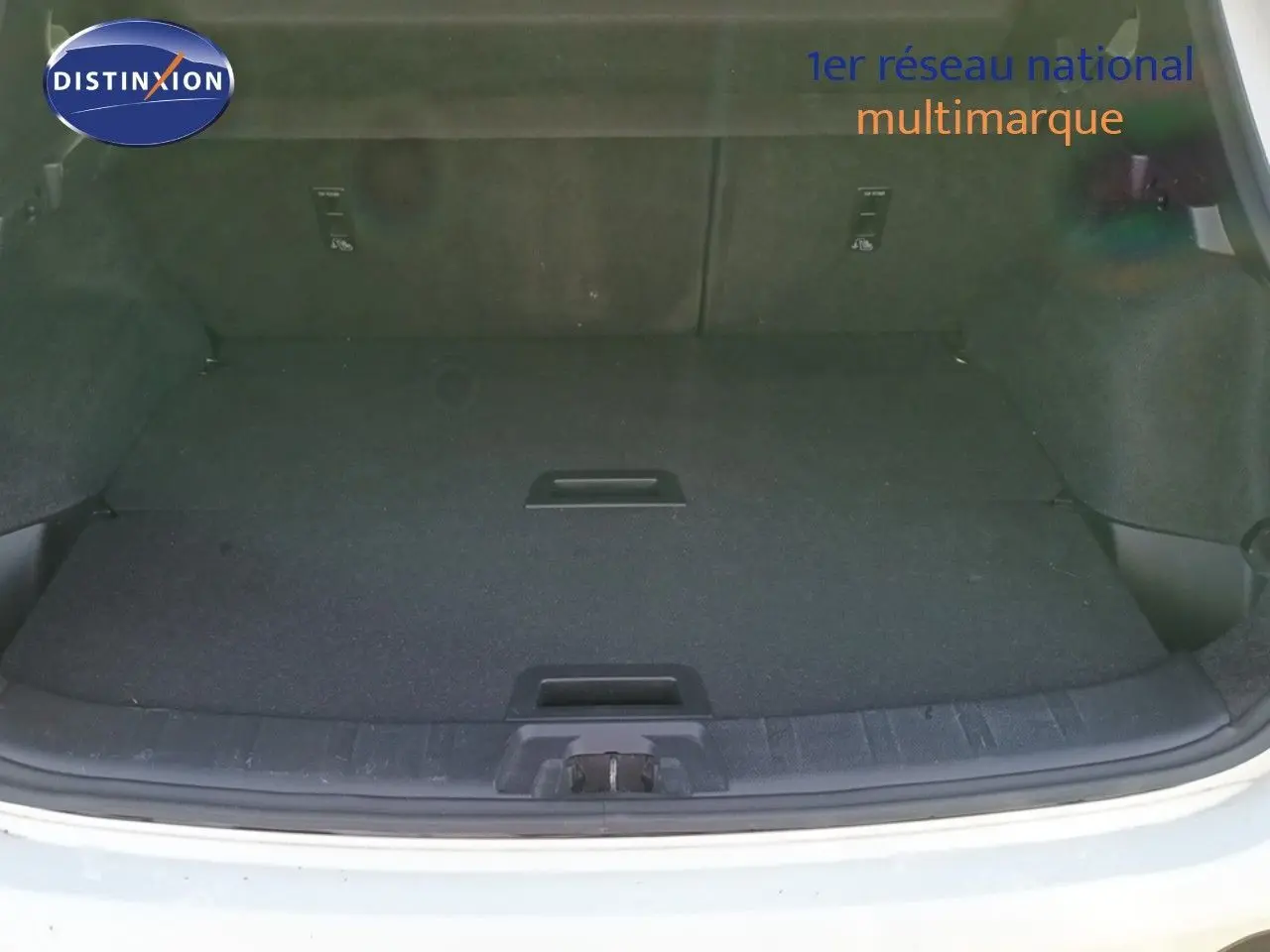 Coffre ouvert vu de l'arrière d'un Nissan Qashqai blanc, espace de chargement plat et propre.