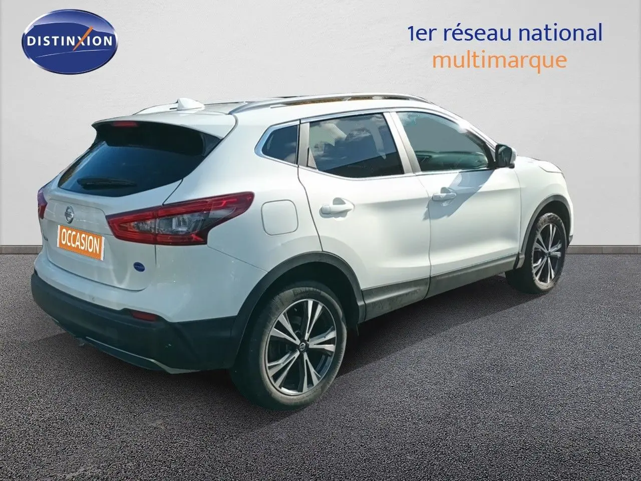 Nissan Qashqai blanc vue 3/4 arrière droit, avec jantes alliage bicolores et vitres teintées.