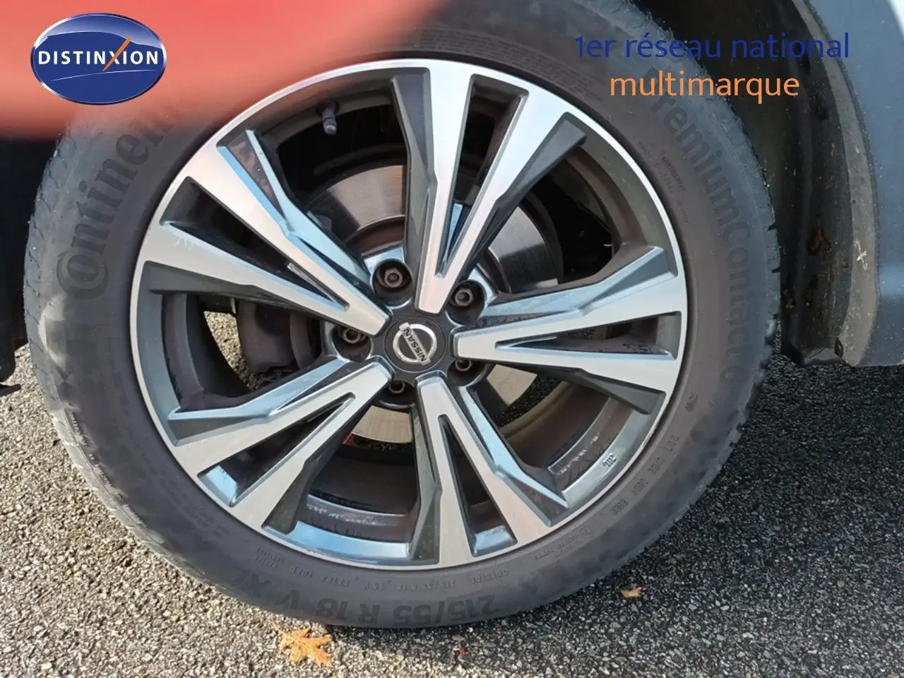 Gros plan sur la roue avant droite du Nissan Qashqai blanc de 2018 avec jante alliage bicolore distinctive.