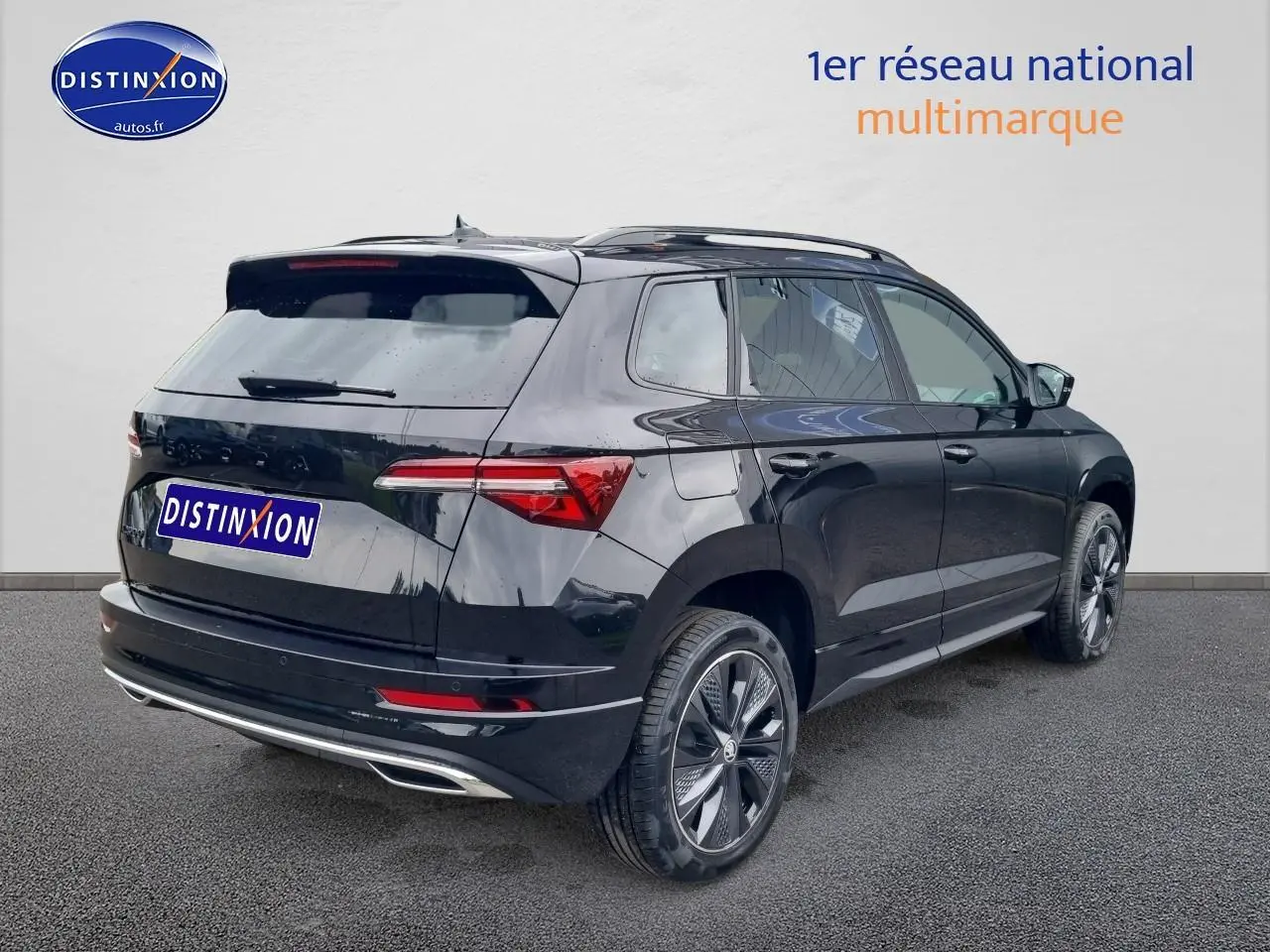 Vue 3/4 arrière droite d’un Skoda Karoq noir 2025 avec jantes alu et barres de toit visibles.