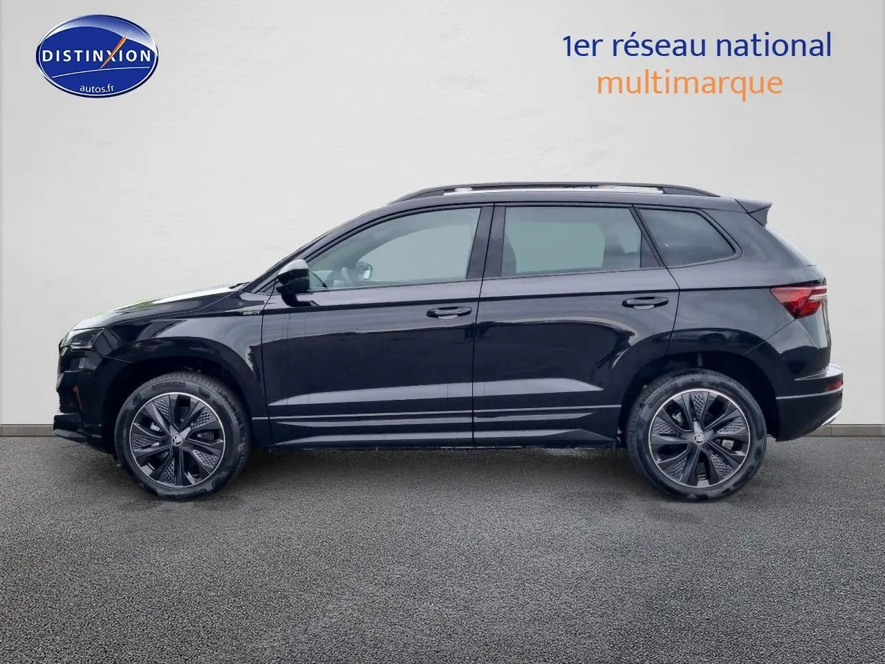 Profil côté gauche d'un Skoda Karoq noir 2025 avec jantes alu et barres de toit visibles sur fond neutre.