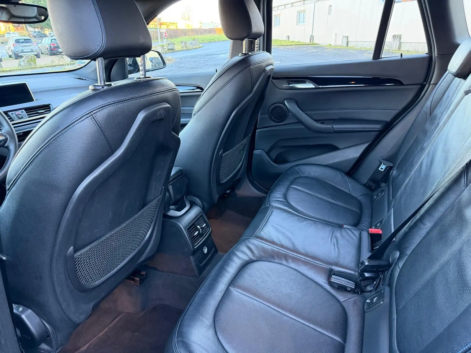 Vue intérieure arrière côté droit du BMW X1 18D M Sport 2018, sièges en cuir noir et console centrale avec aérateurs.