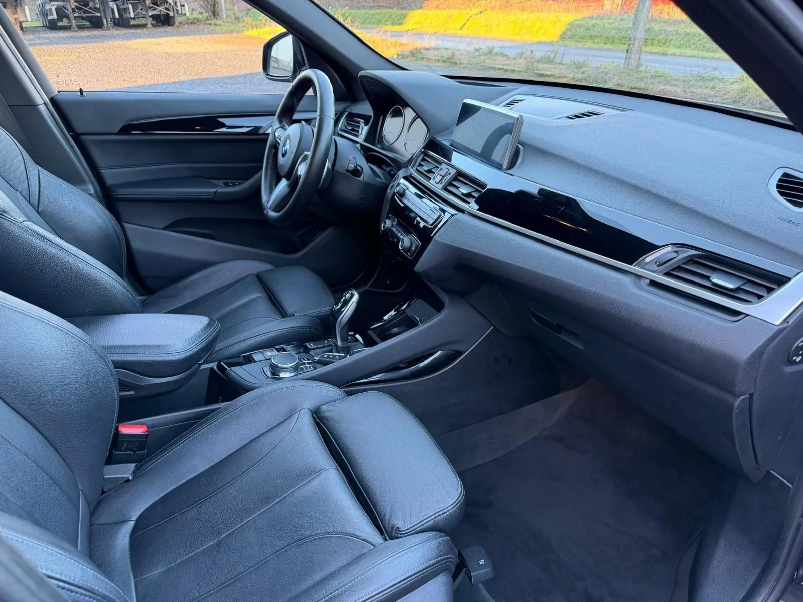 Vue intérieure côté conducteur du BMW X1 18D noir métal, avec sièges en cuir Dakota perforé et tableau de bord moderne.