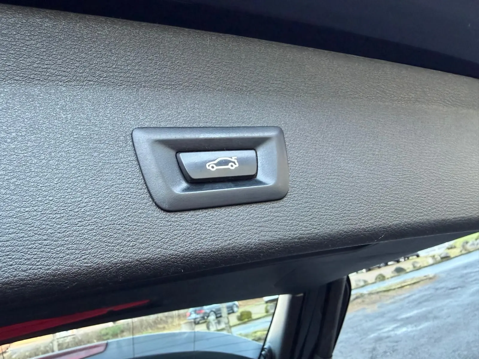 Bouton d'ouverture électrique du hayon sur la garniture intérieure noire du coffre d'un BMW X1 noir métal.