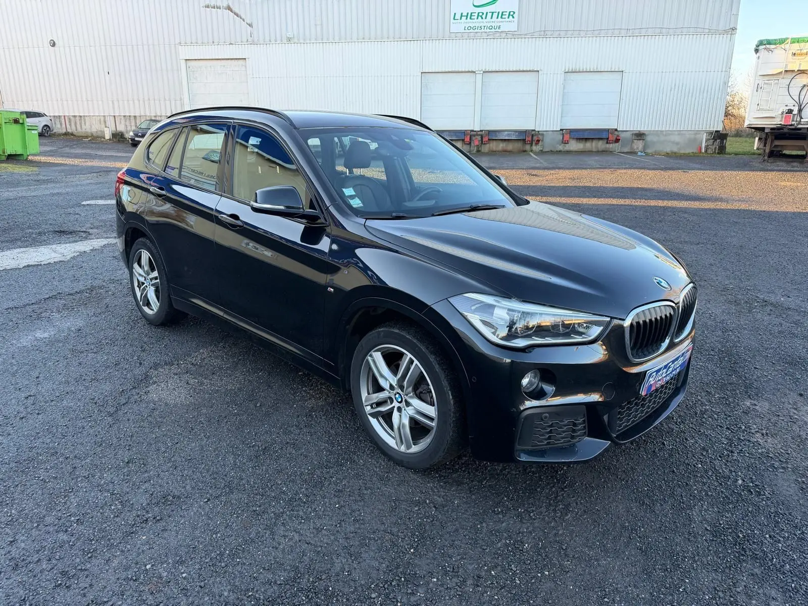 BMW X1 18D M Sport noir métal vue 3/4 avant droit, avec jantes alliage et calandre caractéristique BMW.